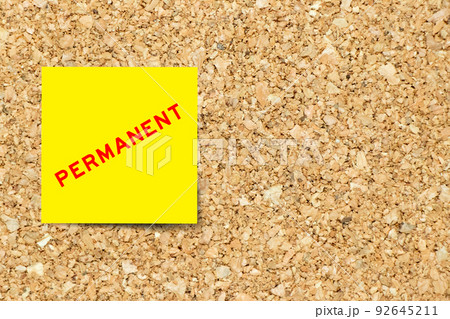 Yellow note paper with word permanent on cork board background with copy space 92645211