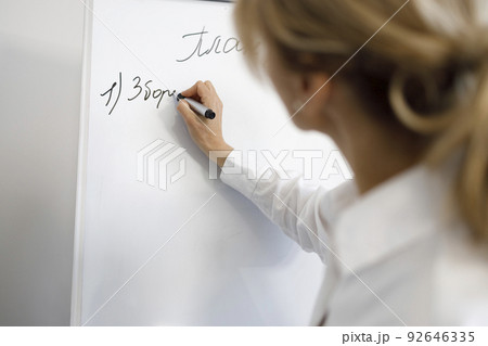 Business woman or teacher writing on a white magnetic flipchart Business woman or teacher writing on a white magnetic flipchart 92646335