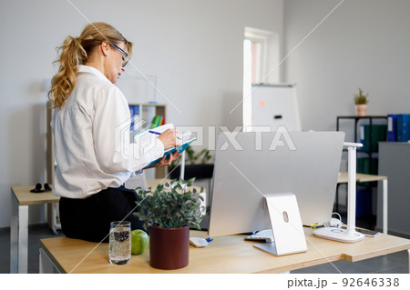 Elegant business woman sitting in the office at the table with a notepad and a pen in her hands 92646338