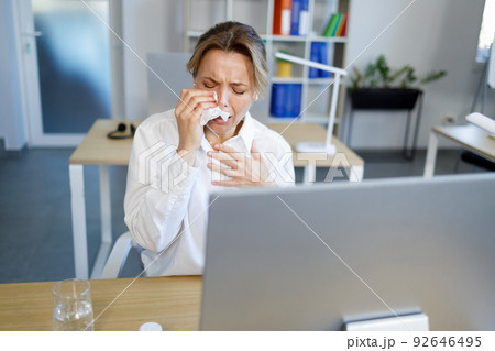 Upset businesswoman crying into handkerchief while sitting at workplace in office Upset businesswoman crying into handkerchief while sitting at workplace in office 92646495