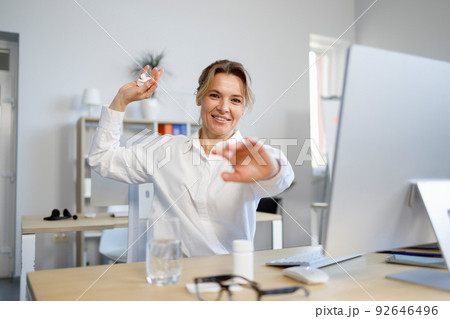 Positive businesswoman sits at her desk and throws crumpled piece of paper into the camera 92646496