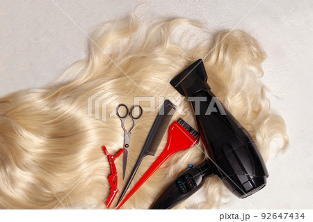Long healthy blond hair and professional scissors, comb and hair dryer, top view 92647434