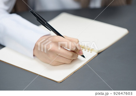 Closeup shot of hand young student lady freelancer journalist writing article using copybook in gray modern home office. Remote Job, Education And Career Profession Concept. Copy space Closeup shot of hand young student lady freelancer journalist writing article using copybook in gray modern home office. Remote Job, Education And Career Profession Concept. Copy space 92647603