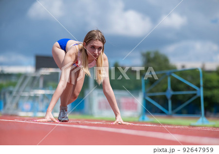 Female runner in the stadium is ready to race. 92647959