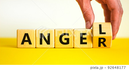 Having anger or being an angel. Businessman turns a wooden cube and changes the word anger to angel. Beautiful white background. Business and anger or angel concept. Copy space. Having anger or being an angel. Businessman turns a wooden cube and changes the word anger to angel. Beautiful white background. Business and anger or angel concept. Copy space. 92648177