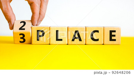 From 3 to 2 place symbol. Businessman turns wooden cubes and changes concept words 3 place to 2 place. Beautiful yellow table white background. Business and from 3 to 2 place concept. Copy space. 92648206
