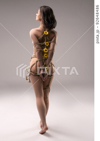 Anonymous naked woman tied with ropes with flowers 92648486