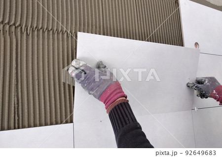 Worker hands putting ceramic tiles on the wall. 92649683