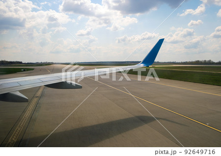 View of jet airplane wing taxiing runway after landing at airport. Travel and air transportation concept. 92649716
