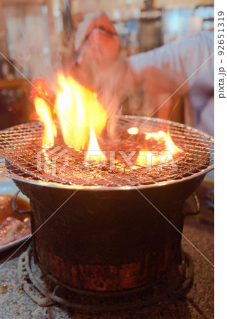 肉から出た脂によって七輪上の網が炎上しているシーン 92651319