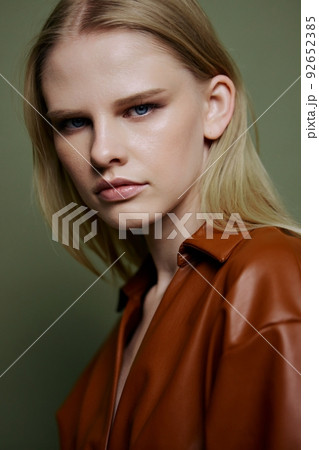 Headshot portrait of stylish confident professional blonde model looks at camera. Closeup shot in studio on over olive green background 92652385