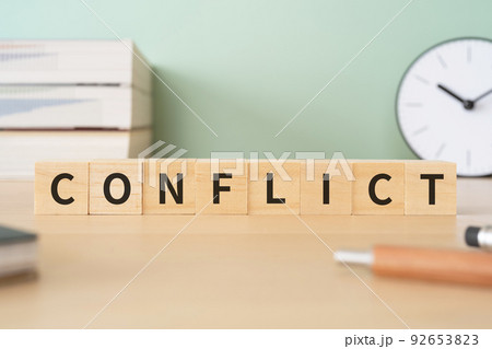 争い・対立・紛争のイメージ｜「CONFLICT」と書かれたブロックが置かれたデスク 92653823