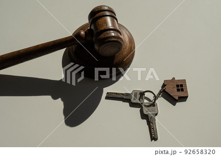 Keys with a keychain in the shape of a house and a judge's gavel on a white background. Keys with a keychain in the shape of a house and a judge's gavel on a white background. 92658320