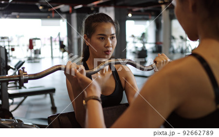 Sporty woman exercising with barbell in fitness class. Workout woman in gym with barbell. Sporty woman exercising with barbell in fitness class. Workout woman in gym with barbell. 92662789