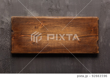 Wooden nameplate or sign board screwed at wall background. Front view of name plate 92663596
