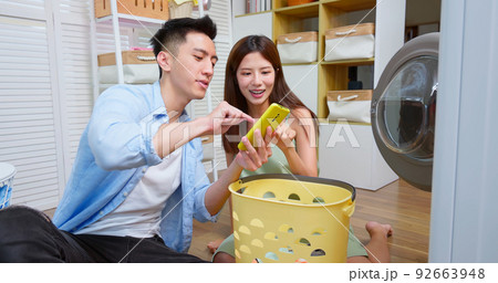 couple using phone control laundry 92663948