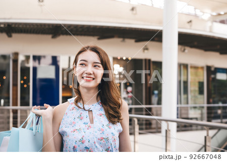 Asian young adult woman In outdoor center mall with shopping bags. Asian young adult woman In outdoor center mall with shopping bags. 92667048