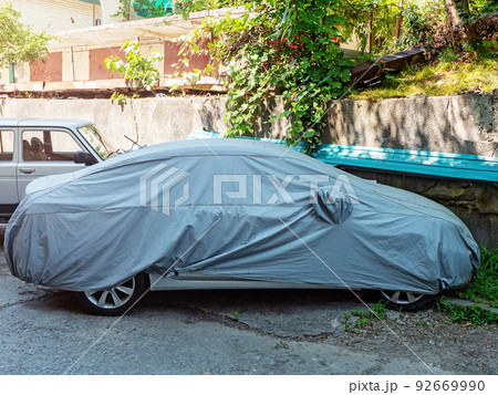 A car covered with a protective cover is parked in the yard 92669990