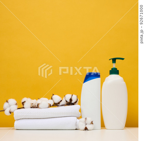 White plastic bottles for gel and shampoo and rolled white terry towels 92671000