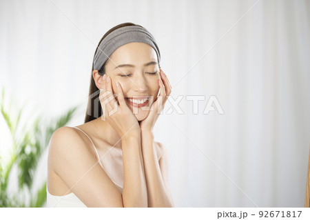 両手を頬に添えて目を閉じる女性 92671817