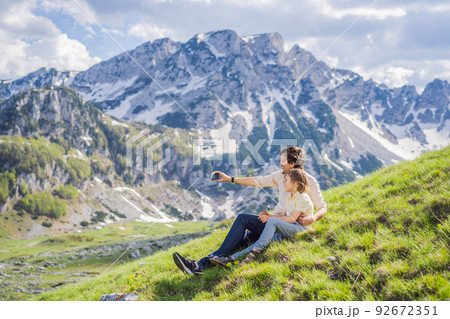 Family of tourists dad and son in Mountain lake landscape on Durmitor mountain in Montenegro beautiful Durmitor National park with lake glacier and reflecting mountain Portrait of a disgruntled girl 92672351