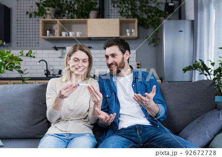 Happy couple man and woman on the couch sitting and rejoicing in a positive pregnancy test 92672728