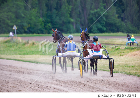 Training and walking horses in chariots. Women jockeys control their animals. 92673241