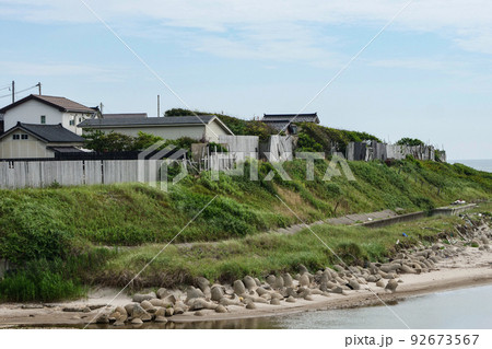 写真 日本海の海の側に立つ家と海岸のゴミ 海風を防ぐ板塀と潮風から守る瓦葺き 写真 日本海の海の側に立つ家と海岸のゴミ 海風を防ぐ板塀と潮風から守る瓦葺き 92673567