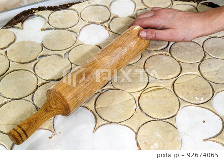 Rolling pin with dough on kitchen table. Preparing dough round tortillas for cookings to be baked. 92674065