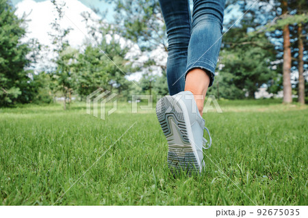 Female legs walking on grass 92675035