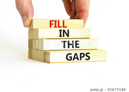 Fill in the gaps symbol. Concept words Fill in the gaps on wooden blocks on a beautiful white table white background. Businessman hand. Business, motivational and fill in the gaps concept. 92675586