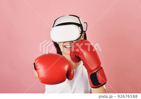 Asian woman hitting a punch by vr glasses, Working out with boxing video games 92676588