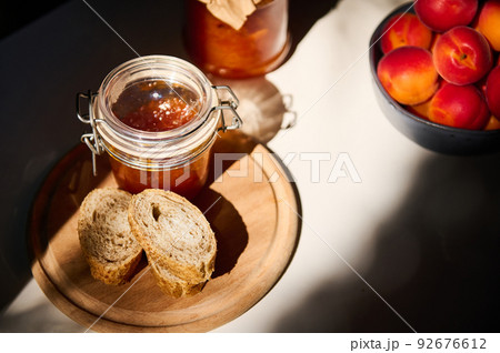 Top view. Slices of whole grain bread on a wooden board, a jar with homemade jam. Still life illuminated by a daylight 92676612