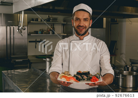 Portrait of cheerful chef standing with cooked traditional japanese sushi 92676613
