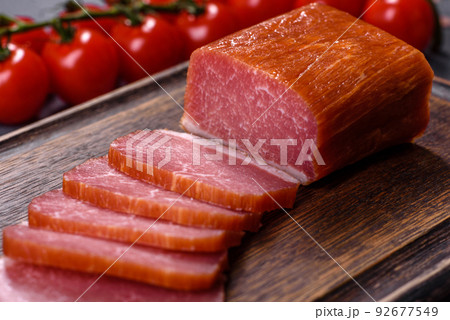 Delicious smoked meat cut with slices on a wooden cutting board Delicious smoked meat cut with slices on a wooden cutting board 92677549