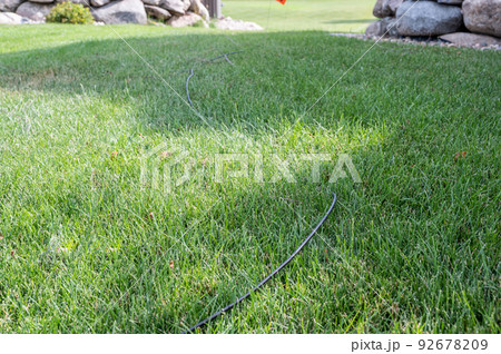 Fiber optic cable laying in the grass ready to be installed at a residential house. Fiber optic cable laying in the grass ready to be installed at a residential house. 92678209