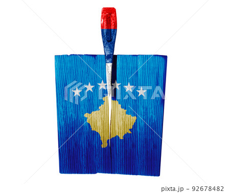 The butt of an ax painted in the colors of the flag of Serbia strikes at the flag of Kosovo. Balkan war. Serbia attack. Serbia's war against Kosovo. 92678482
