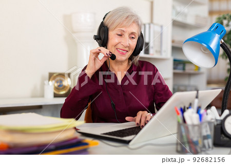 Smiling female operator talking with customer using headset at office Smiling female operator talking with customer using headset at office 92682156
