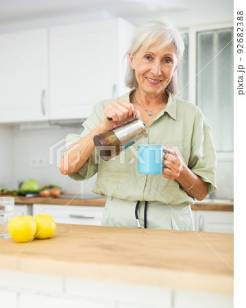 Cheerful senior woman pouring fresh coffee into mug 92682388