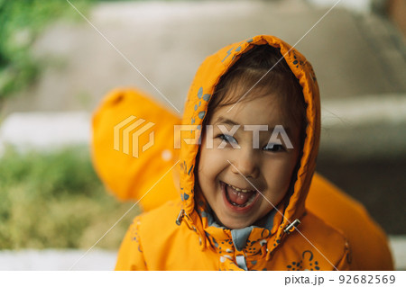 Children in yellow rain suits standing in the rain Children in yellow rain suits standing in the rain 92682569