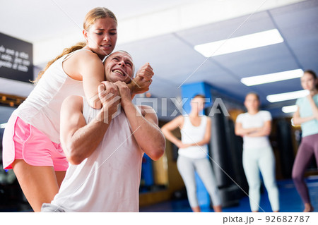 Girl practicing guillotine choke on opponent in sparring with man 92682787