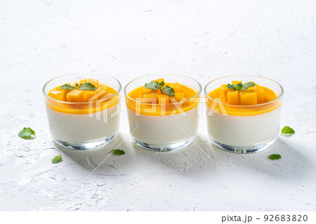 Delicious double colored mango panna cotta mousse pudding on white table background. Delicious double colored mango panna cotta mousse pudding on white table background. 92683820