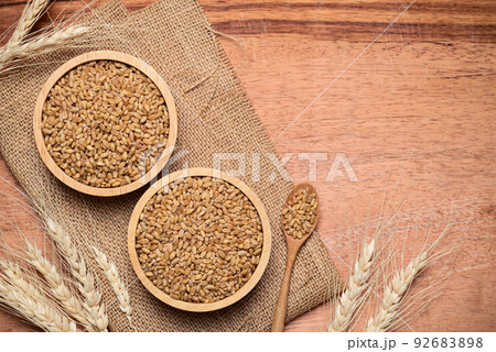 Whole wheat grain in bowl on wooden background, food ingredients, Table top view 92683898
