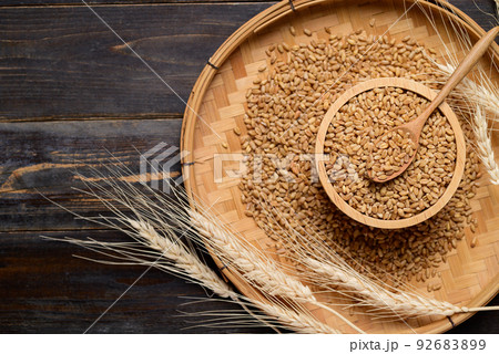 Whole wheat grain in bowl with spoon on wooden background, food ingredients, Table top view 92683899
