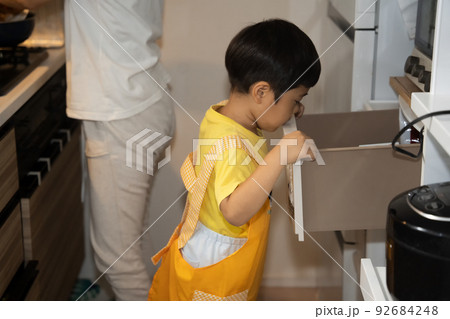 お母さんの料理の手伝いをしようと、棚の中にある何かを探す4歳男児 お母さんの料理の手伝いをしようと、棚の中にある何かを探す4歳男児 92684248