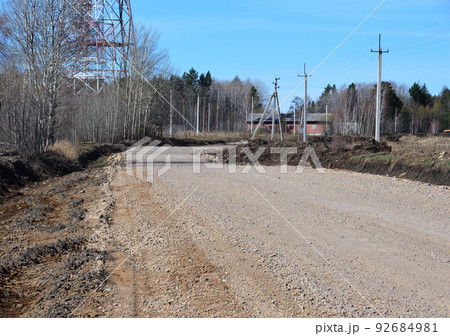 Country road with curb. Metal construction and red brick buildings. Road landscape. Photo project `Country roads`. Country road with curb. Metal construction and red brick buildings. Road landscape. Photo project `Country roads`. 92684981