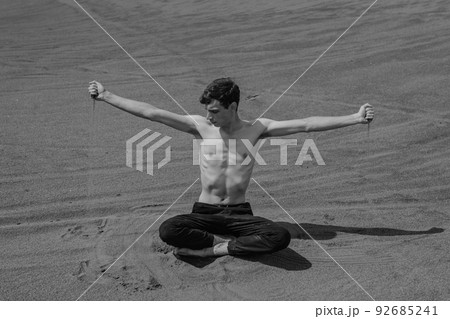 Man sitting on the sand dune and pouring sand through hand in desert 92685241