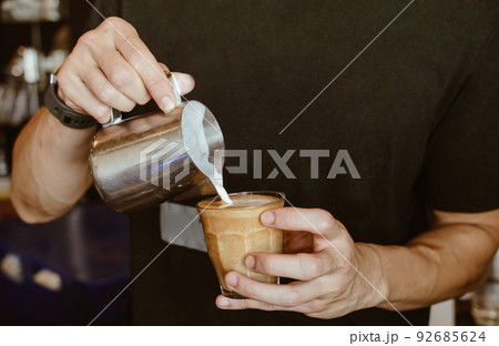Cropped shot of Barista making cappuccino/latte by pouring milk in coffee cup for make latte art. 92685624