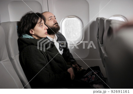 Caucasian travellers having conversation on commercial flight, travelling by plane to go on holiday journey destination. Couple flying abroad with airplane transport to arrive on vacation. Caucasian travellers having conversation on commercial flight, travelling by plane to go on holiday journey destination. Couple flying abroad with airplane transport to arrive on vacation. 92691161