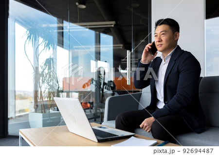 Thinking asian businessman businessman, talking on the phone working in a modern office, listening seriously Thinking asian businessman businessman, talking on the phone working in a modern office, listening seriously 92694487